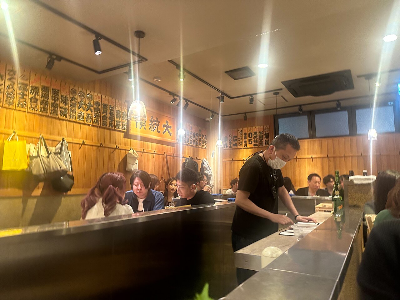Suasana izakaya dengan pengunjung di meja bar